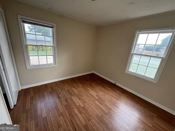 an empty room with wooden floor and windows