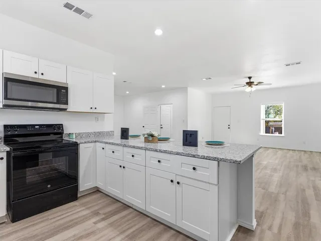 a kitchen with stainless steel appliances granite countertop a stove a sink and a microwave