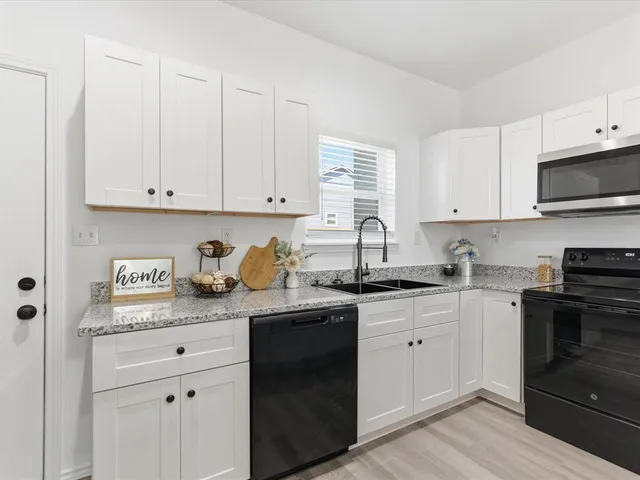 a kitchen with granite countertop white cabinets sink and stainless steel appliances