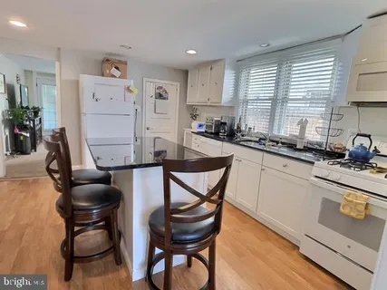 a kitchen with stainless steel appliances granite countertop a table chairs sink and cabinets