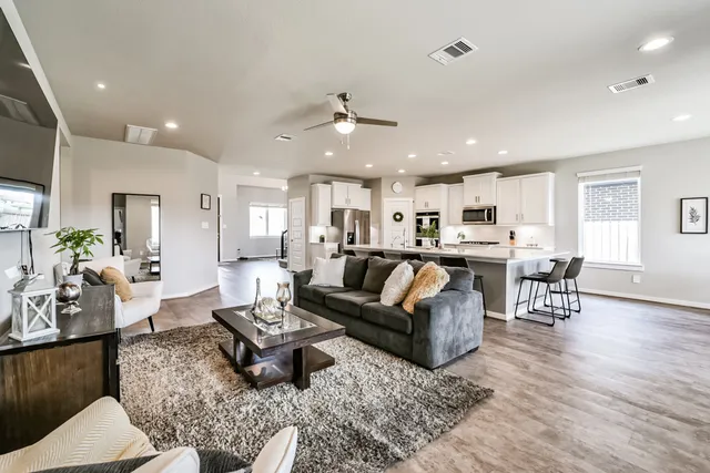 a living room with furniture kitchen view and a wooden floor