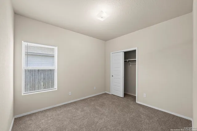 a view of an empty room with closet and a window
