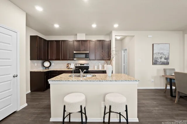 a kitchen with stainless steel appliances granite countertop a table chairs sink refrigerator and cabinets
