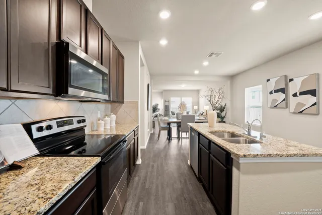 a kitchen with stainless steel appliances granite countertop a stove top oven a sink dishwasher and cabinets with wooden floor