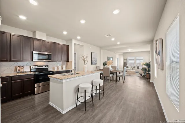 a kitchen with kitchen island granite countertop wooden floors and white stainless steel appliances