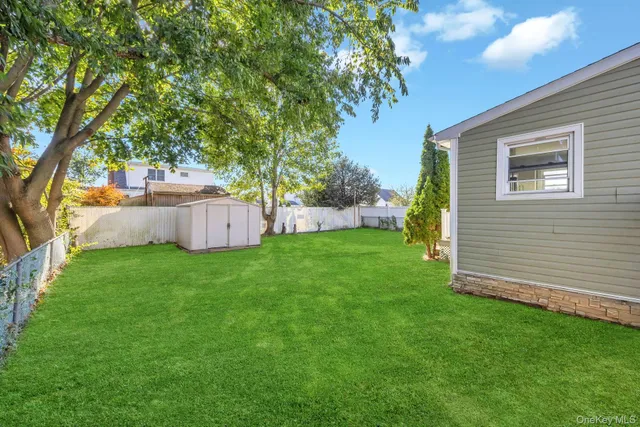 a view of a backyard with large tree and wooden fence