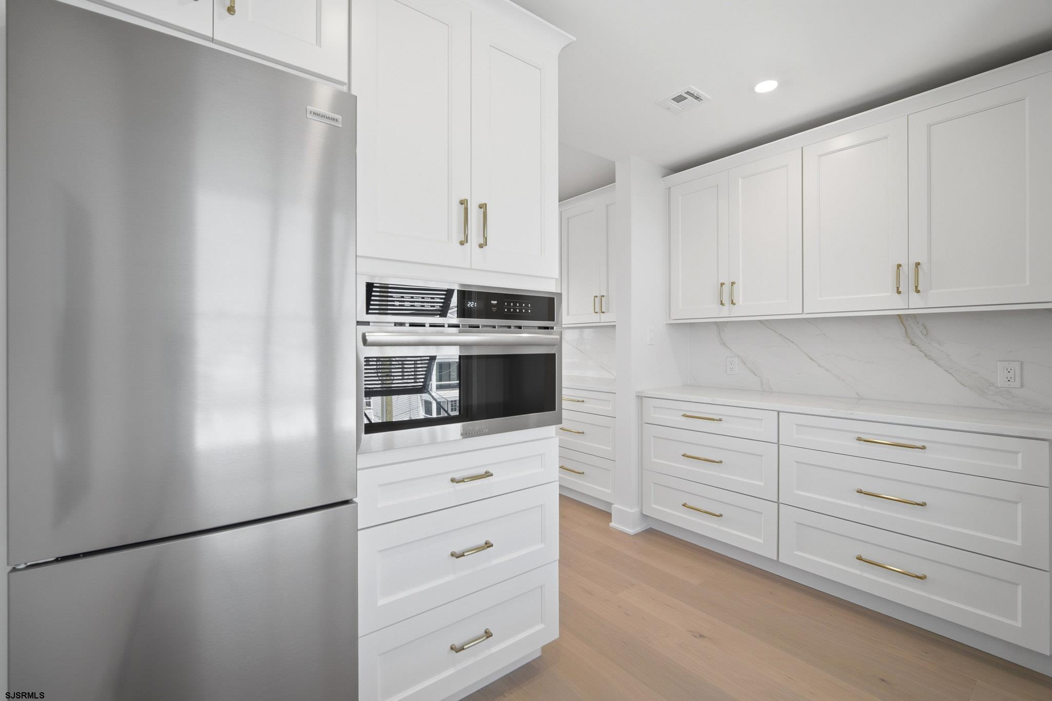 230 7th Street South Brigantine, NJ 08203 - Photo 55 of 87 a kitchen with white cabinets and stainless steel appliances