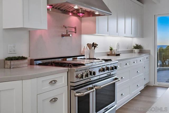 a kitchen with a stove and white cabinets