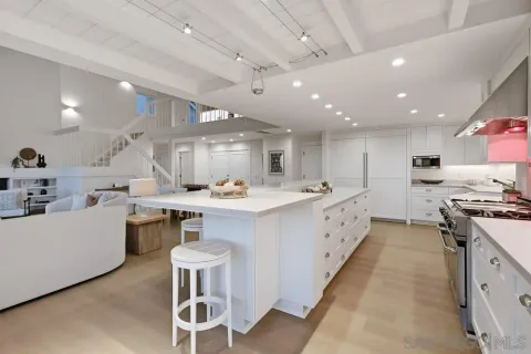 a large white kitchen with stainless steel appliances lots of counter space and windows