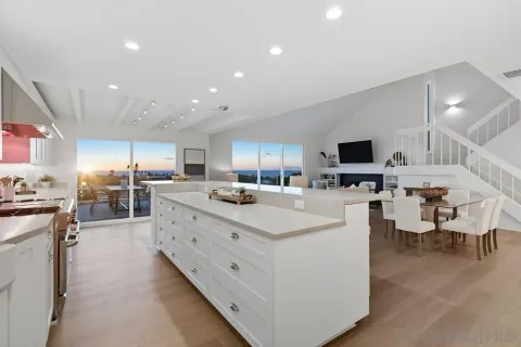 a large white kitchen with a large window and white cabinets