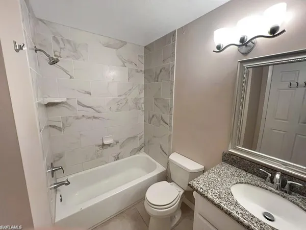a bathroom with a granite countertop sink toilet mirror and shower