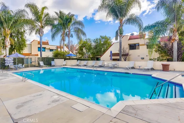 a view of swimming pool with outdoor seating and house in the background