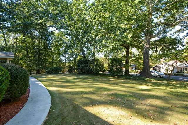 a view of a swimming pool with a yard and large trees