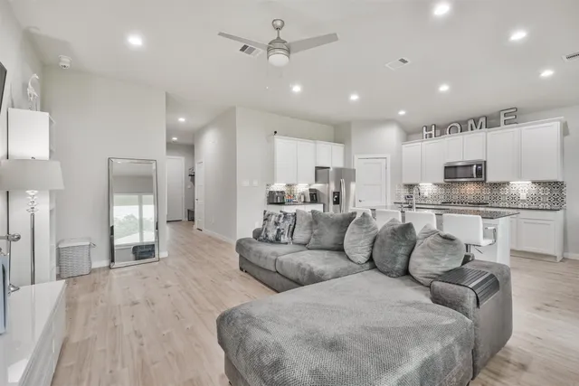 a large living room with stainless steel appliances kitchen island granite countertop a couch and a view of living room