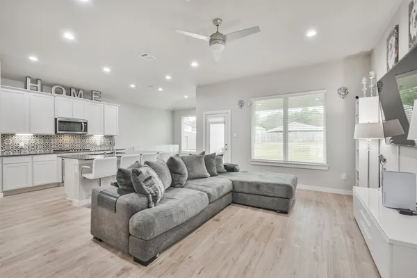 a living room with couches and kitchen view with wooden floor