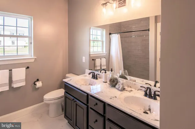 a bathroom with a granite countertop sink a toilet and a mirror