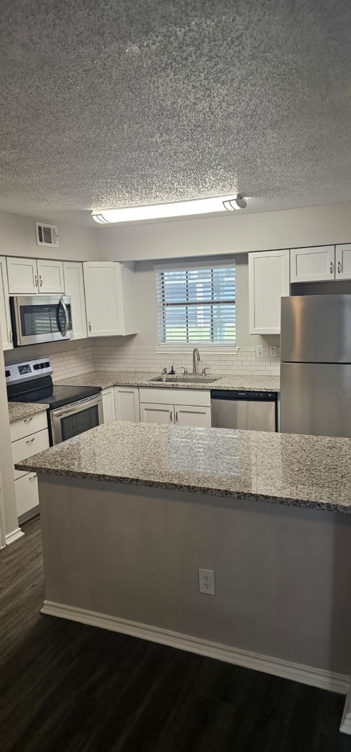 3737 Timberglen Road, Unit 909 Dallas, TX 75287 - Photo 3 of 19 a kitchen with granite countertop a refrigerator a sink and wooden cabinets