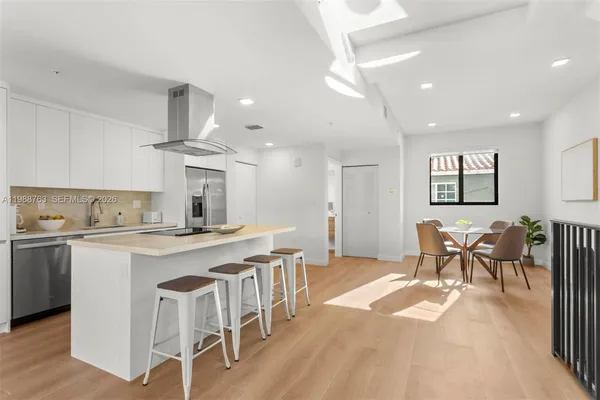 a open kitchen with stainless steel appliances granite countertop a stove a refrigerator a kitchen island a dining table and chairs with wooden floor