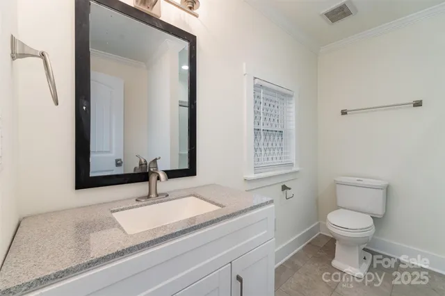 a bathroom with a granite countertop sink mirror vanity and toilet