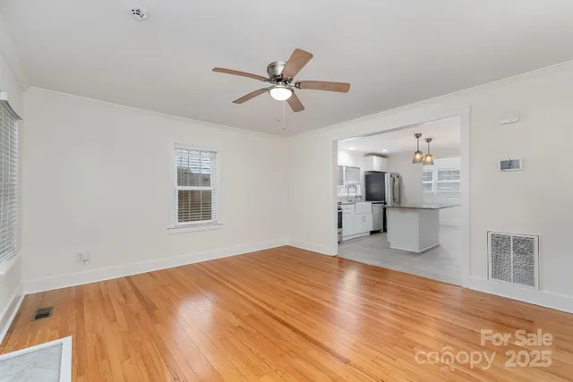 a view of empty room with wooden floor and ceiling fan