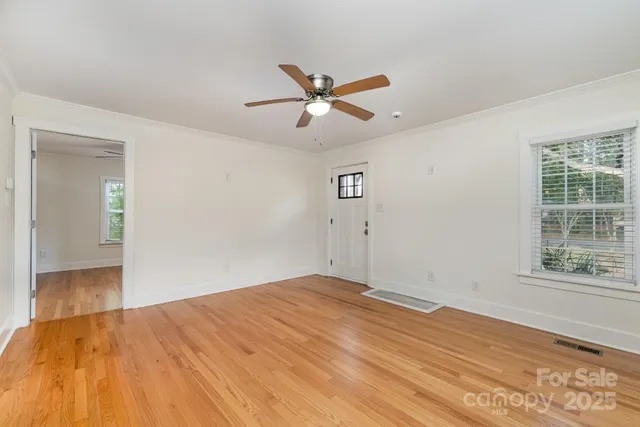 a view of empty room with wooden floor and fan