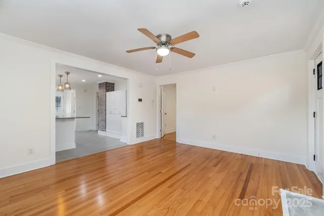 a view of empty room with wooden floor and fan