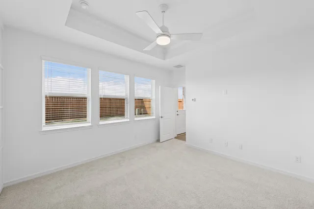 an empty room with a ceiling fan and windows