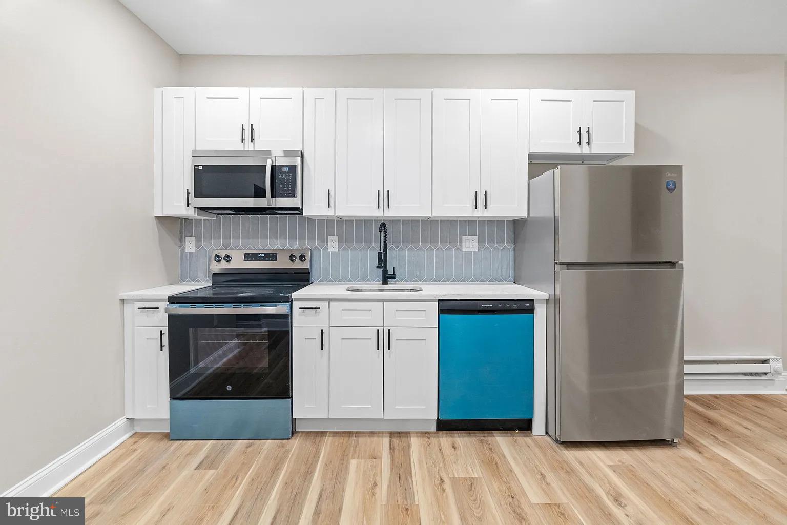 6232 Reedland Street, Unit 1 Philadelphia, PA 19142 - Photo 3 of 8 a kitchen with a refrigerator stove and white cabinets