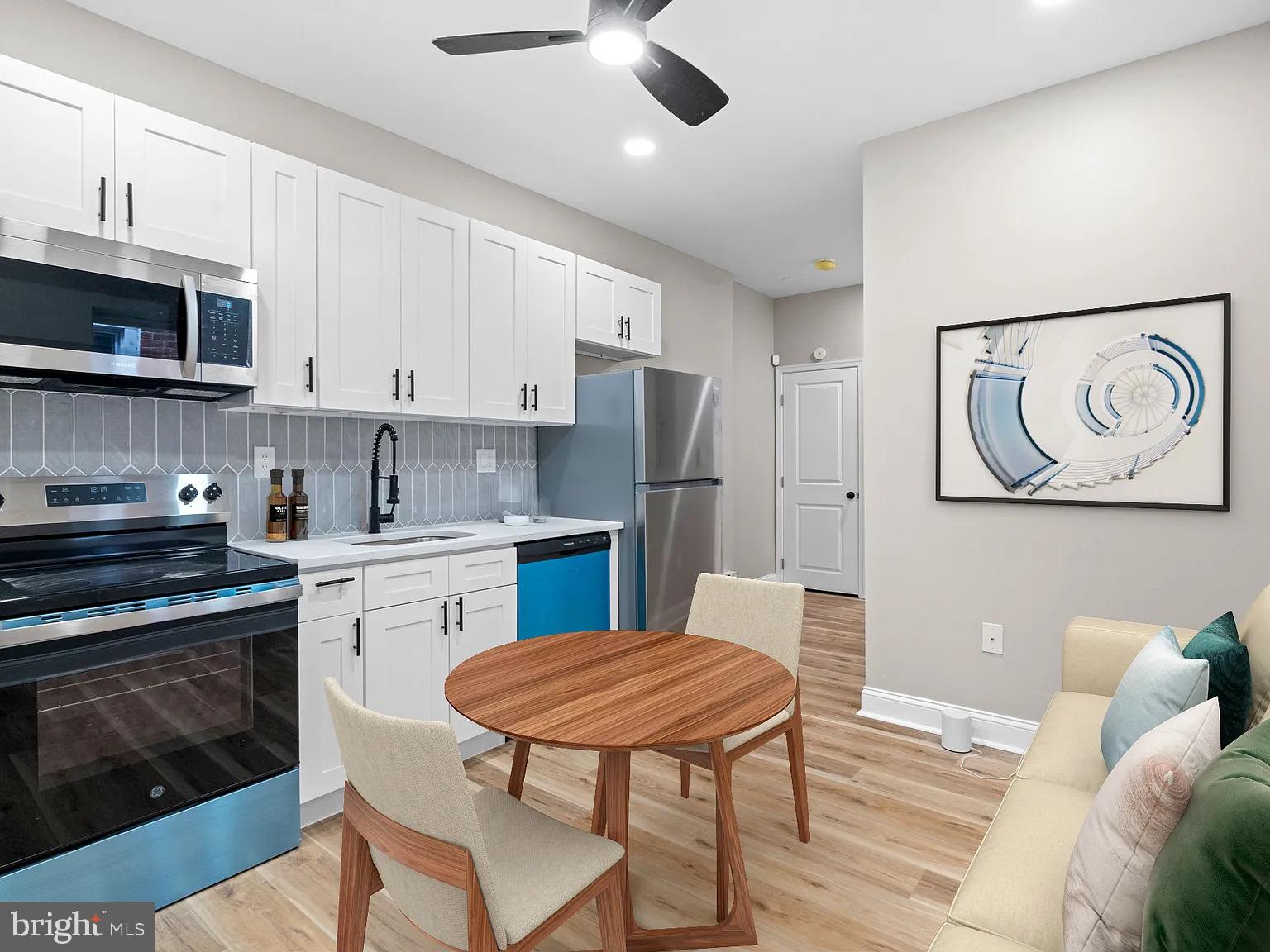 6232 Reedland Street, Unit 1 Philadelphia, PA 19142 - Photo 6 of 8 a kitchen with stainless steel appliances granite countertop a stove a refrigerator a kitchen island a sink dishwasher a dining table and chairs with wooden floor