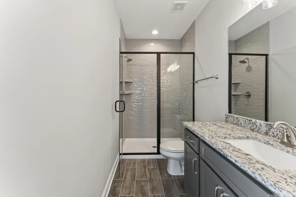 a bathroom with a granite countertop sink a mirror and shower