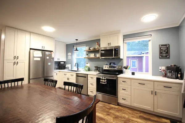 a kitchen with stainless steel appliances granite countertop a stove refrigerator a sink dishwasher a dining table and chairs with wooden floor