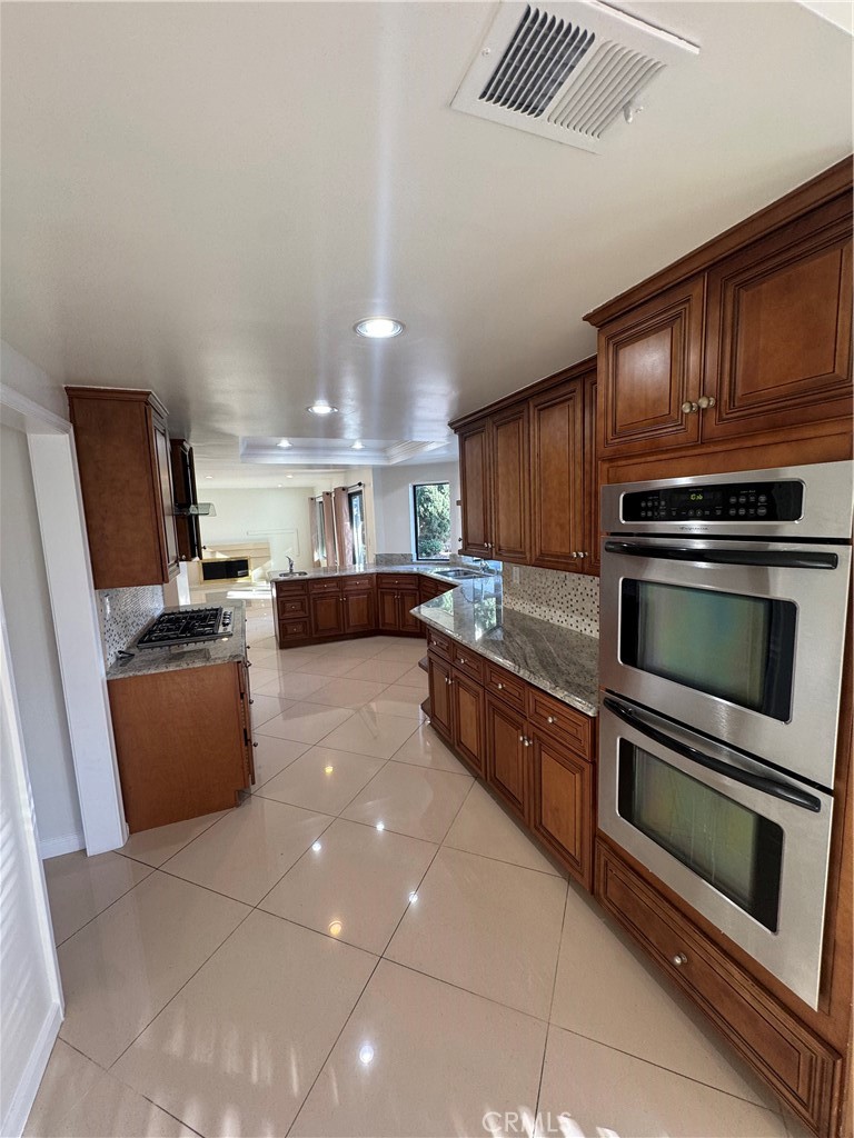 11445 Etiwanda Avenue Porter Ranch, CA 91326 - Photo 11 of 28 a kitchen with stainless steel appliances kitchen island granite countertop a stove a sink dishwasher and a microwave oven on the blue kitchen countertops with wooden floor