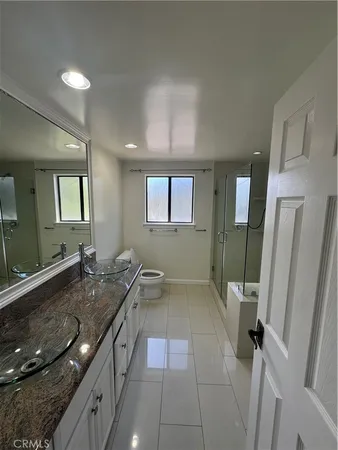 a spacious bathroom with a granite countertop sink a toilet a mirror and vanity