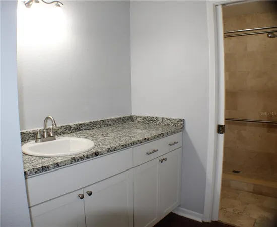 a bathroom with a granite countertop sink and a mirror