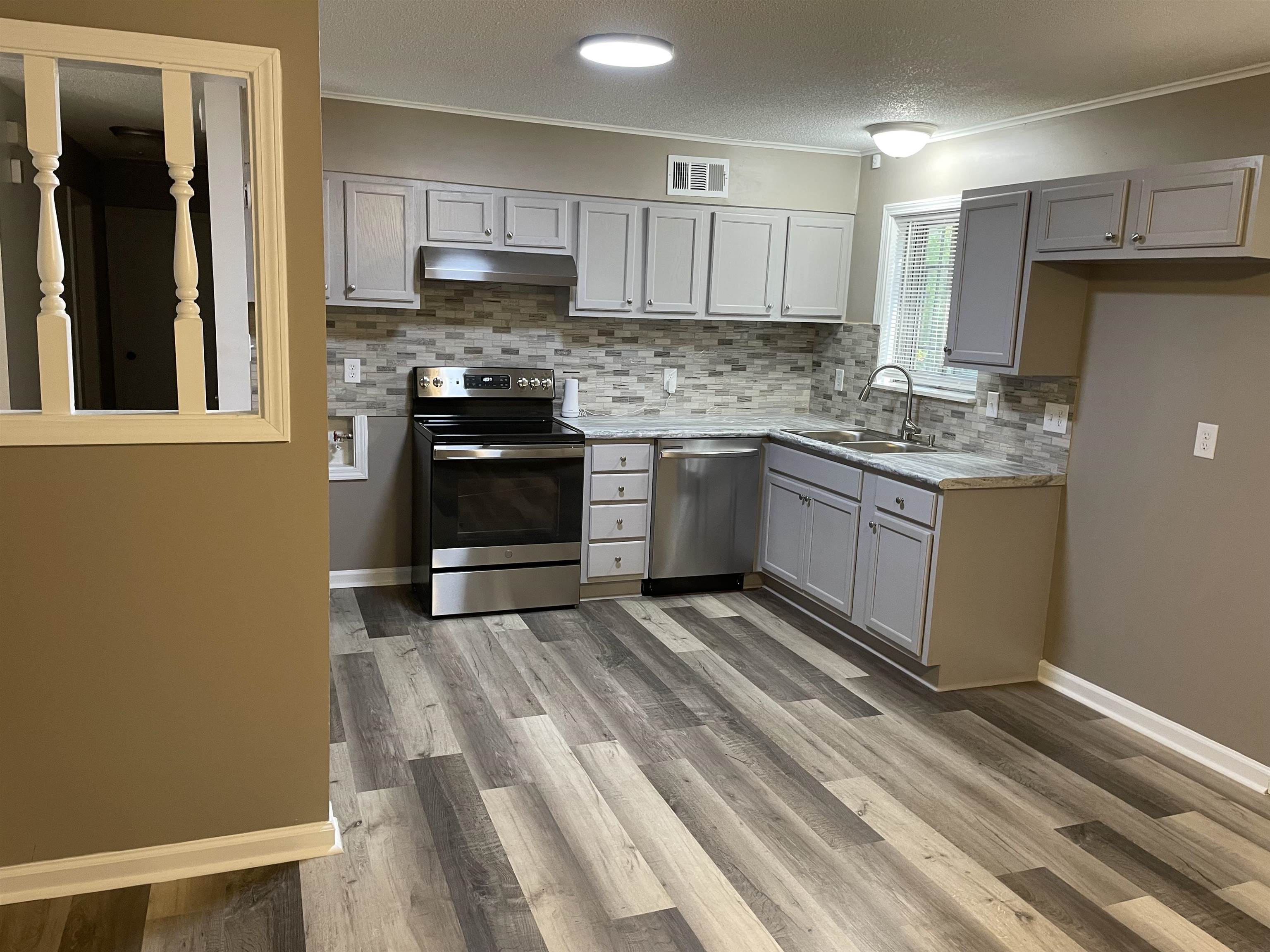 4615 Berta Road Memphis, TN 38109 - Photo 3 of 19 a kitchen with granite countertop a stove top oven and cabinets
