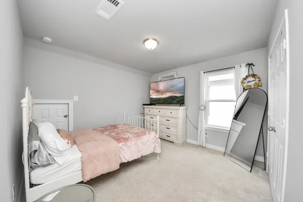 a bedroom with a bed and a flat tv screen on the dresser