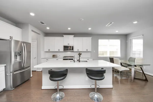 a kitchen with stainless steel appliances a table chairs and a refrigerator
