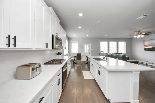 a large white kitchen with stainless steel appliances granite countertop a lot of counter space a sink and dishwasher