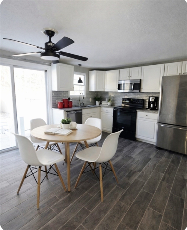 39 Adelaide Avenue, Unit 1 Methuen, MA 01844 - Photo 2 of 8 a kitchen with stainless steel appliances a dining table chairs and a refrigerator