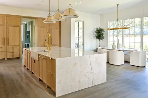 a large room with kitchen island a large counter top space a sink stainless steel appliances and cabinets