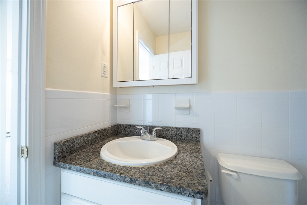 3 Dailey Street, Unit J Attleboro, MA 02703 - Photo 21 of 24 a bathroom with a granite countertop sink and a mirror