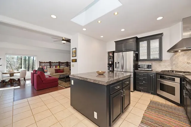 a kitchen with stainless steel appliances granite countertop a stove top oven a sink dishwasher a dining table and chairs with wooden floor