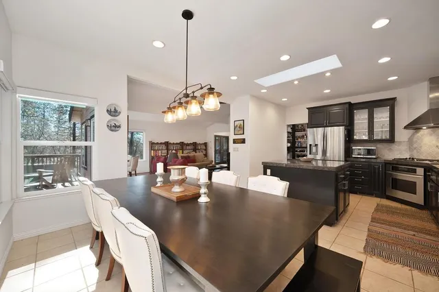 a large kitchen with stainless steel appliances granite countertop a sink a stove and a dining table with wooden floor