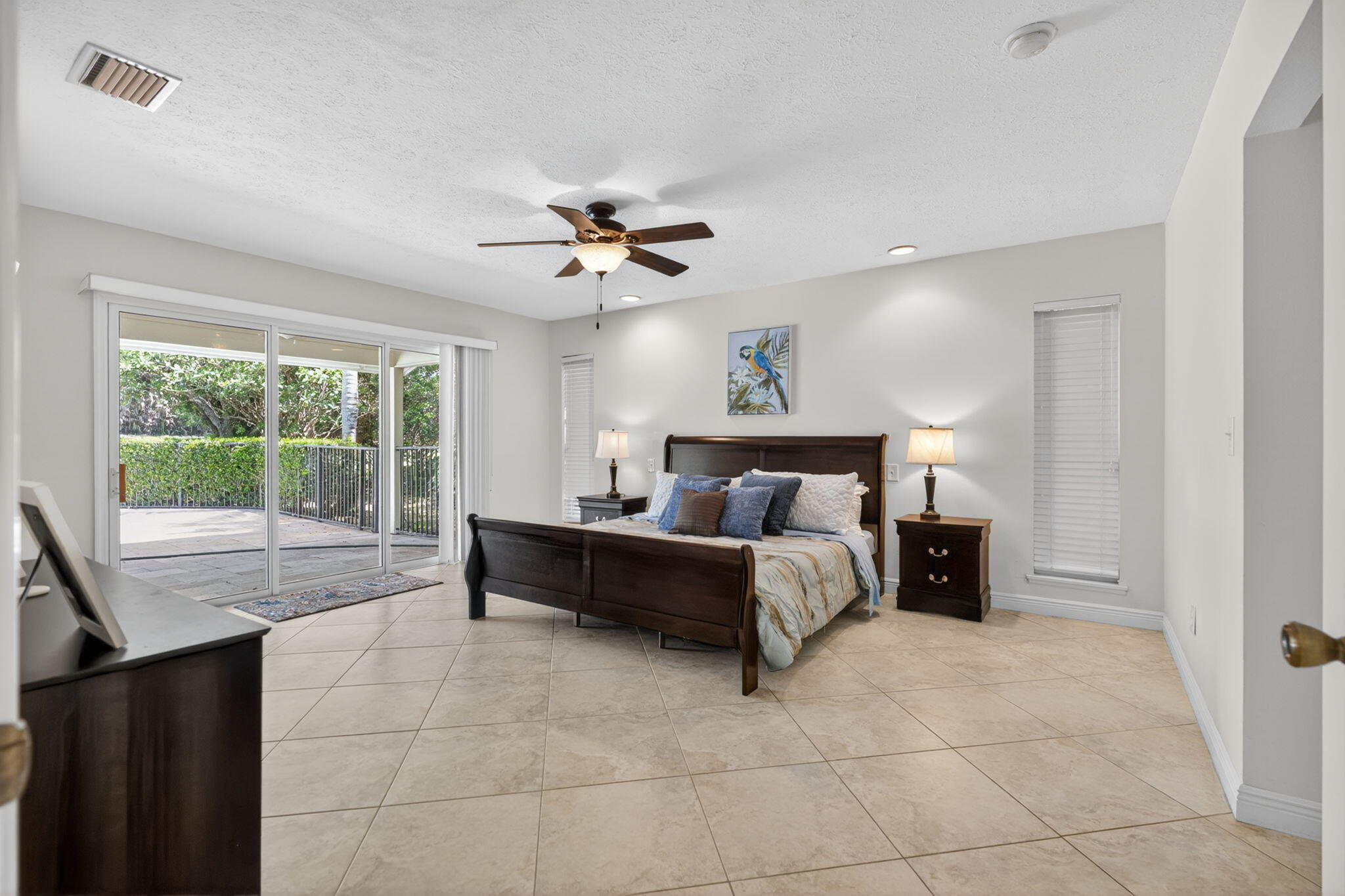 5741 Southeast Winged Foot Drive Stuart, FL 34997 - Photo 16 of 58 a spacious bedroom with a bed and a chandelier