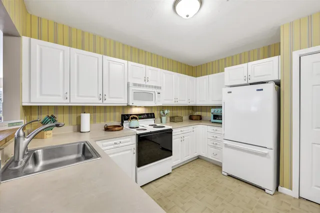 a kitchen with granite countertop white cabinets and white appliances