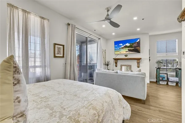 a living room with stainless steel appliances furniture a flat screen tv and a refrigerator