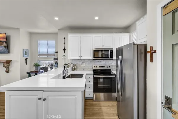 a kitchen with a sink a refrigerator and a stove top oven with wooden floor