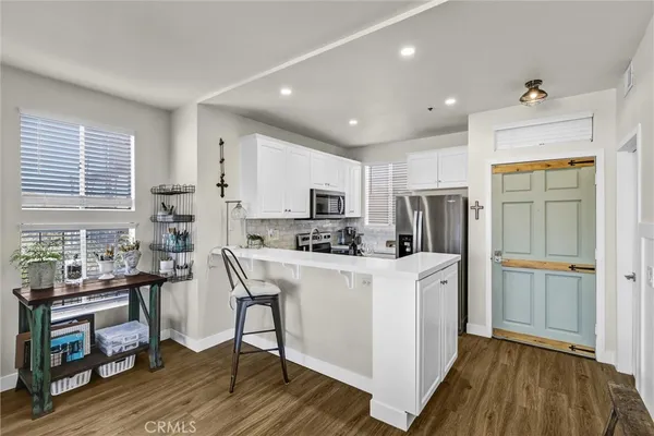 a kitchen with stainless steel appliances a stove a refrigerator a sink dishwasher and a dining table with wooden floor