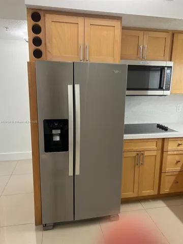 a view of a refrigerator in kitchen and an empty room