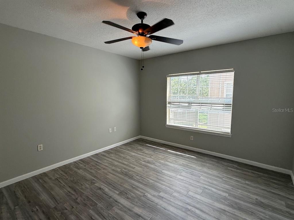 4817 Cypress Woods Drive, Unit 5203 Orlando, FL 32811 - Photo 12 of 22 an empty room with wooden floor and windows